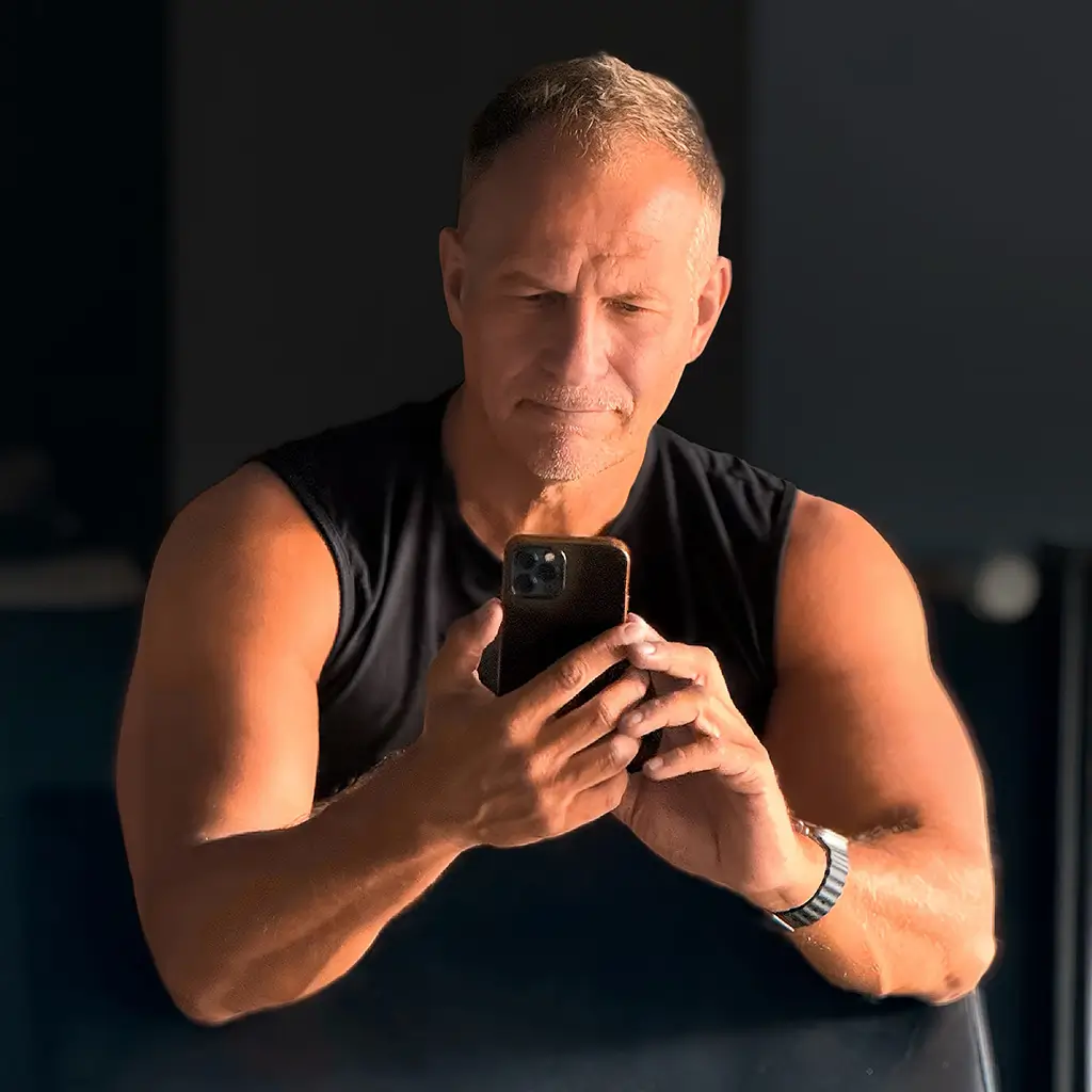 Achim Loobes im Gym – fokussiert auf das iPhone, zwischen Training und App-Entwicklung