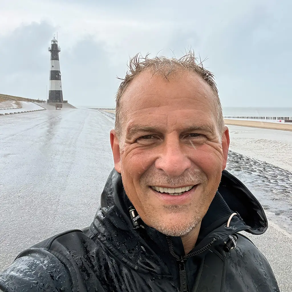 Achim Loobes bei Regen an der Nordseeküste von Breskens mit Leuchtturm im Hintergrund