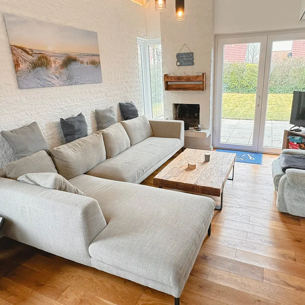 Wohnzimmer im Scheldesand – helle Couch, Naturbild, harmonische Einrichtung